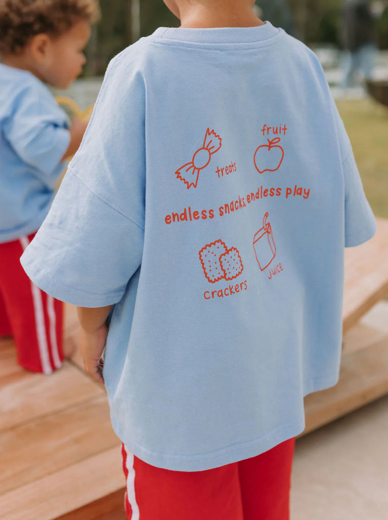 Child wearing a light blue t-shirt with red text and graphics outdoors.